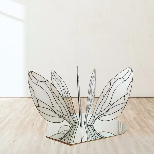Installation d'ailes en vitrail déposées verticalement et en cercle sur un miroir.